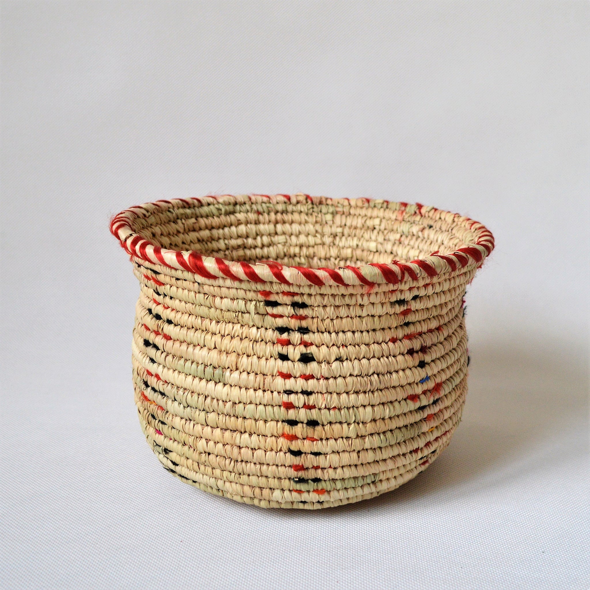 Wide woven bowl decorated with red and black fabric